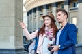 Happy love couple of tourists taking photo on excursion or city tour. Photos on the background of urban architecture