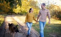 Happy love couple walking in park with german shepherd dog, holding hands and look each other Royalty Free Stock Photo