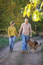 Happy love couple walking in park with their german shepherd dog, holding hands Royalty Free Stock Photo