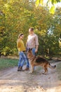 Happy love couple walking in park with their german shepherd dog, holding hands Royalty Free Stock Photo