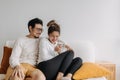 Happy lovely asian couple sharing smartphone to watch together in living room