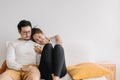 Happy lovely asian couple sharing smartphone to watch together in living room