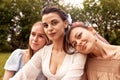 Happy lovely bride in a white dress and two bridesmaids in a blue and beige dress sit in a summer park on the grass and