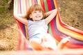 Happy lovely child girl relaxing in colorful hammock in summer forest Royalty Free Stock Photo