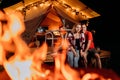 Happy lovely couple relaxing in glamping on evening near cozy bonfire. Luxury camping tent for outdoor recreation and recreation.