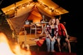 Happy lovely couple relaxing in glamping on evening near cozy bonfire. Luxury camping tent for outdoor recreation and recreation. Royalty Free Stock Photo