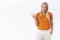 Happy, lovely feminine stylish blond woman in orange t-shirt trendy pants, hold hand in pocket, show peace or victory