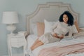 Happy lovely pregnant female relaxing on bed at home and touching her belly Royalty Free Stock Photo