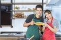 Happy lovely young Asian couple in love with casual clothes is smiling, helping to prepare, cooking food as omelet together in Royalty Free Stock Photo