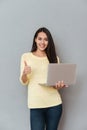 Happy lovely young woman holding laptop and showing thumbs up Royalty Free Stock Photo