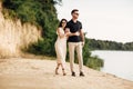 Happy lovers at the beach near lake. Young couple is holding hands and walking on summer day outdoors. A man and woman in love. Royalty Free Stock Photo