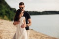 Happy lovers at the beach near lake. Young couple is hugging at sunset on summer day outdoors. A man and woman in love. Concept of Royalty Free Stock Photo