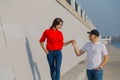 Happy lovers walk along the promenade holding hands.