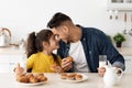 Happy Loving Arab Father And Little Daughter Eating Snacks In Kitchen Together