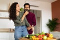 Happy loving arab woman cutting salad and feeding her husband in kitchen interior, copy space Royalty Free Stock Photo