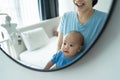 Happy Loving Asian mother and cute little baby boy looking and smiling at their faces in mirror at home together. Cheerful Young Royalty Free Stock Photo