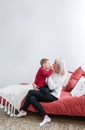 Happy loving blonde mother and her son are sitting in a bedroom. Mother hugs son Royalty Free Stock Photo