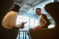 Happy loving couple, business partners, handsome man and pretty woman resting together, sitting on armchairs in airport departure Royalty Free Stock Photo