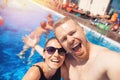 Happy loving couple Caucasian man and woman hugging and making selfie photo on background of pool. Smile and tanned skin