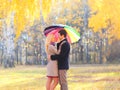 Happy loving couple with colorful umbrella in warm sunny day over yellow flying leafs