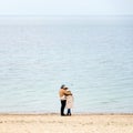 Happy loving couple embracing wearing warm clothes standing on ocean coast. Cold season, sea shore, empty beach in Royalty Free Stock Photo