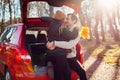 Happy loving couple enjoying date in car trunk hugging in autumn forest at sunset. Husband and wife travel by auto. Royalty Free Stock Photo