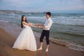 Happy loving couple newlyweds hold each others hands on ocean beach. Beautiful bride and groom at wedding day outdoors Royalty Free Stock Photo