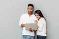 Happy loving couple over grey wall chatting by laptop Royalty Free Stock Photo