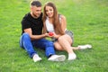 Happy loving couple with red heart sitting on green grass outdoors Royalty Free Stock Photo