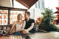 Happy loving couple sitting on terrace in cozy restaurant and smiling. Smiling young man and girl sitting at table in cafe and