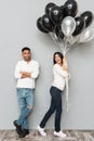 Happy loving couple standing over grey wall with balloons Royalty Free Stock Photo
