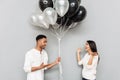 Happy loving couple standing over grey wall with balloons Royalty Free Stock Photo