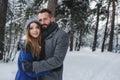 Happy loving couple walking in snowy winter forest, spending christmas vacation together. Outdoor seasonal activities Royalty Free Stock Photo