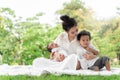 Happy loving family. Asian young beautiful mother and her children, new born baby girl and a boy sitting on green grass to playing Royalty Free Stock Photo