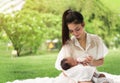 Happy loving family. Asian young beautiful mother and holding her newborn child touching gently and feeding baby bottle with love Royalty Free Stock Photo