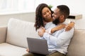 Happy loving african american couple sitting on couch, using laptop Royalty Free Stock Photo