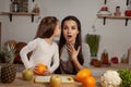 Mother and her daughter are doing a fruit cutting and having fun at the kitchen.