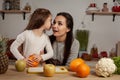 Mother and her daughter are doing a fruit cutting and having fun at the kitchen.