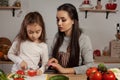 Mother and her daughter are making a vegetable salad and having fun at the kitchen. Royalty Free Stock Photo