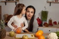 Mother and her daughter are doing a fruit cutting and having fun at the kitchen.