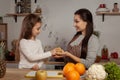 Mother and her daughter are doing a fruit cutting and having fun at the kitchen.