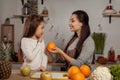 Mother and her daughter are doing a fruit cutting and having fun at the kitchen.