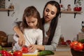 Mother and her daughter are making a vegetable salad and having fun at the kitchen. Royalty Free Stock Photo