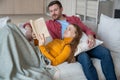 Happy loving family couple staying at home, relaxing, reading interesting novel, discussing on couch Royalty Free Stock Photo