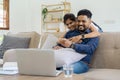 Happy loving family Indian couple hugging on couch at home and focused on laptop screen watching romantic movie Royalty Free Stock Photo