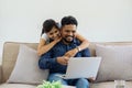 Happy loving family Indian couple hugging on couch at home and focused on laptop screen watching romantic movie Royalty Free Stock Photo