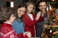 Happy loving family involved in decorating x-mas festive evergreen tree. Royalty Free Stock Photo