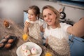 Happy loving family in the kitchen. Mother and child daughter girl are eating cookies they have made and having fun in