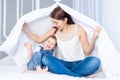 A happy, loving family. Mom and baby son play at home on the bed under the blanket Royalty Free Stock Photo