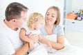 Happy and loving family morning concept. Cheerful parents in sleepwear having fun with their daughter on the bed. Family spending Royalty Free Stock Photo